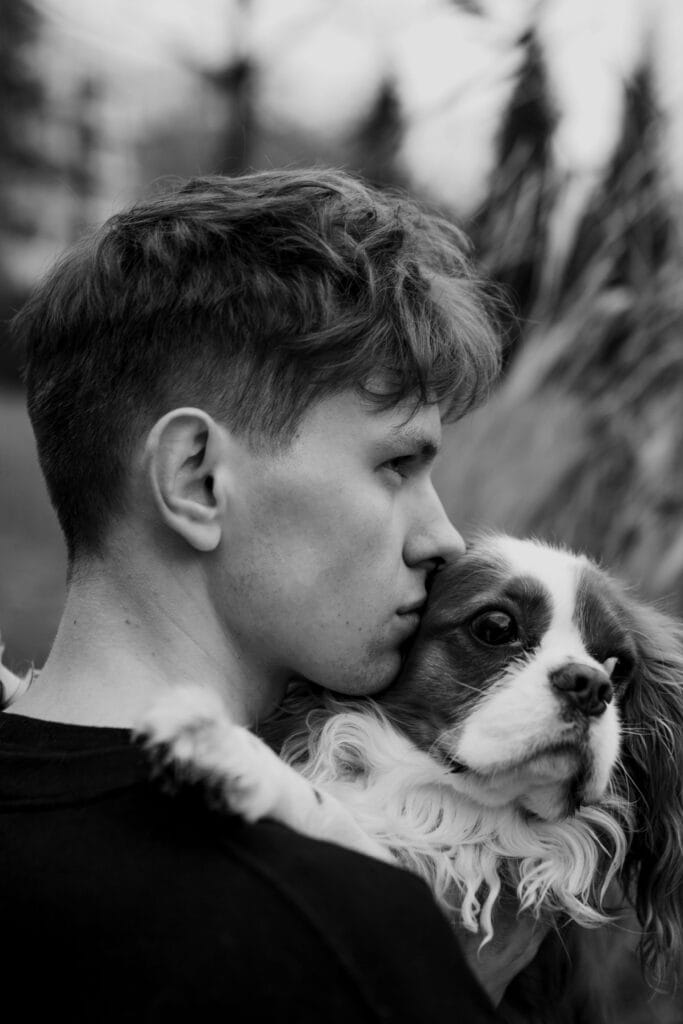 Black and white side portrait of a man embracing his Cavalier King Charles Spaniel.