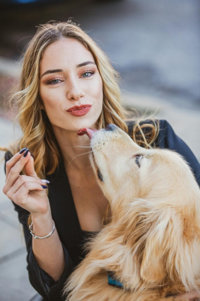 Why Do Dogs Lick People?, Woman enjoying playful interaction with her Golden Retriever outdoors.