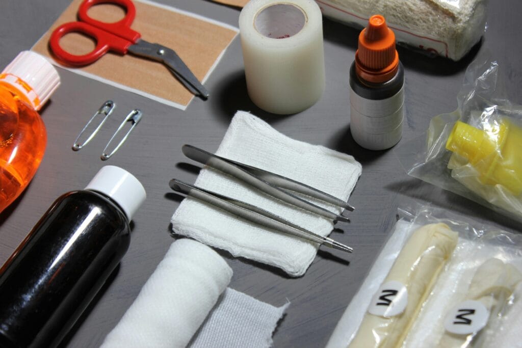 High-angle view of various essential first aid items, including bandages, gauze, scissors, and disinfectants on a table.